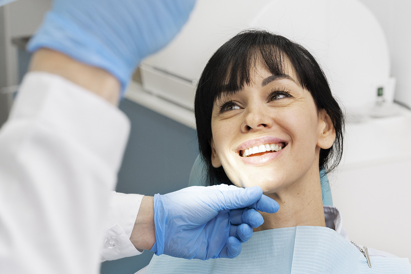 Smiling female patient receiving dental examination from dentist in clinical setting.