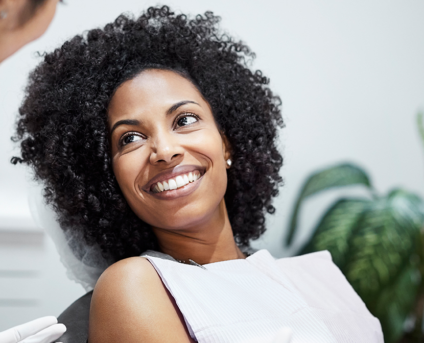 Happy woman smiling in dental office with potted plant in background